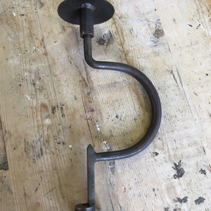 Puede incluir: Un taladro de manivela vintage con un mango de metal negro y una base redonda de metal. El taladro está hecho de metal y tiene una punta afilada.