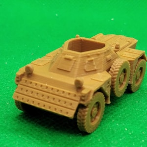Può includere: Un modello in plastica color beige di un'auto blindata militare con una torretta girevole. Il modello ha quattro ruote ed è dettagliato con una superficie testurizzata.