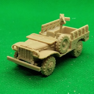 Könnte beinhalten: Ein beigefarbenes Modell eines Militärjeeps mit montiertem Maschinengewehr. Das Miniaturfahrzeug verfügt über detaillierte Reifen, eine vordere Stoßstange und ein Ersatzrad an der Seite. Der Jeep steht vor einem grünen Hintergrund.