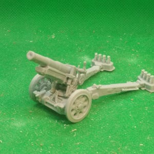 May include: A light gray scale model of a field artillery cannon featuring a long barrel, two spoked wheels, and two extended trail legs with spade ends. The miniature weapon is constructed with intricate mechanical details and a matte finish.