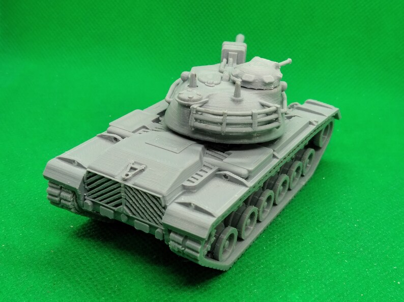 May include: A gray plastic model of a tank with a detailed turret and tracks. The tank has a raised gun barrel and a protective cage around the turret.