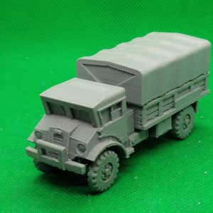 May include: A gray model of a military truck with a canvas tarp covering the bed. The truck has a detailed cab and wheels.