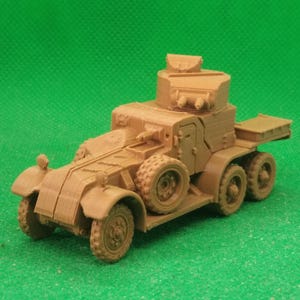 May include: A tan-coloured model of an armoured car with six wheels, a turret, and a rear storage area. The model is set against a solid green background. The vehicle has detailed features.