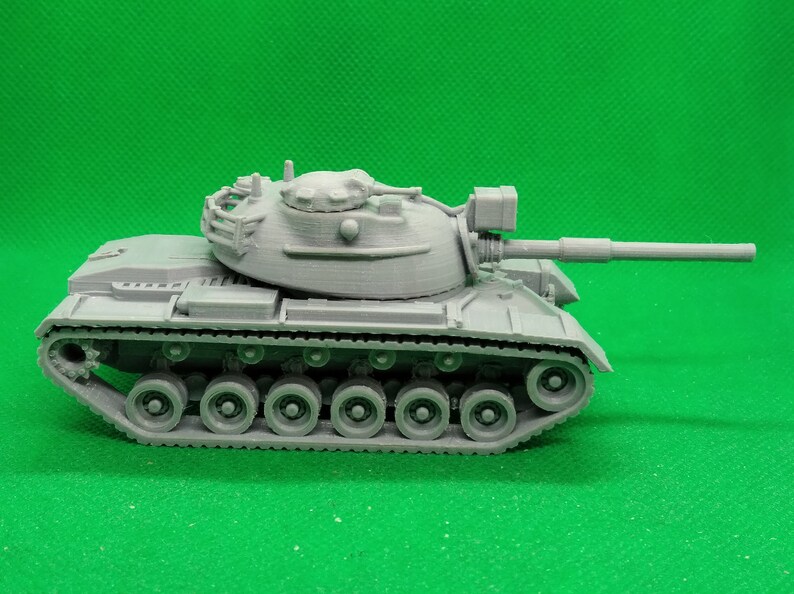 May include: A gray plastic model of a tank with a long barrel and a detailed turret. The tank has a series of wheels on each side and a track.
