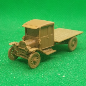 May include: A brown toy model of a vintage truck with a wooden bed. The truck has a cab with a windshield and a door. The truck is on a green surface.