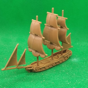 May include: A miniature brown toy ship with three masts and sails, set against a green background. The ship has detailed features, including a deck and rigging, and is likely a model or collectible item.