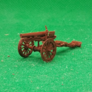 Könnte beinhalten: Ein Miniaturmodell einer braunen Kanone mit zwei Speichenrädern und einem langen Lauf. Die Kanone steht vor einem grünen Hintergrund, was auf ein Spielzeug oder Sammlerstück hindeutet. Das Modell scheint aus einem festen Material zu bestehen.