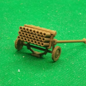 Op de afbeelding: Een bruin plastic model van een anti-vliegtuigkanon uit de Tweede Wereldoorlog met een groot aantal vaten. Het kanon staat op wielen en heeft een lange loop.