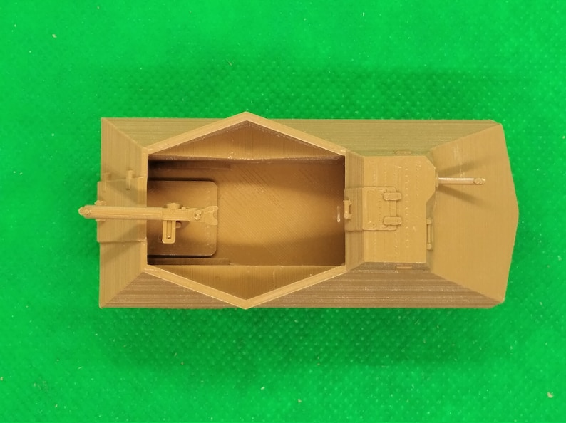 May include: A tan-colored plastic model of a military vehicle with a gun turret and a cannon. The model is detailed with a textured surface and is viewed from above.