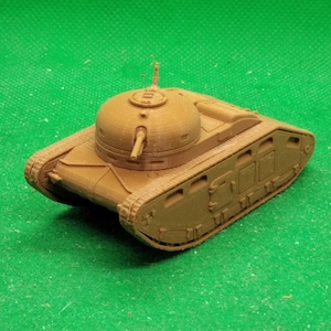 May include: A tan-colored model tank with a rounded turret and a gun barrel. The tank has detailed treads and is set against a green background. The model appears to be 3D-printed.