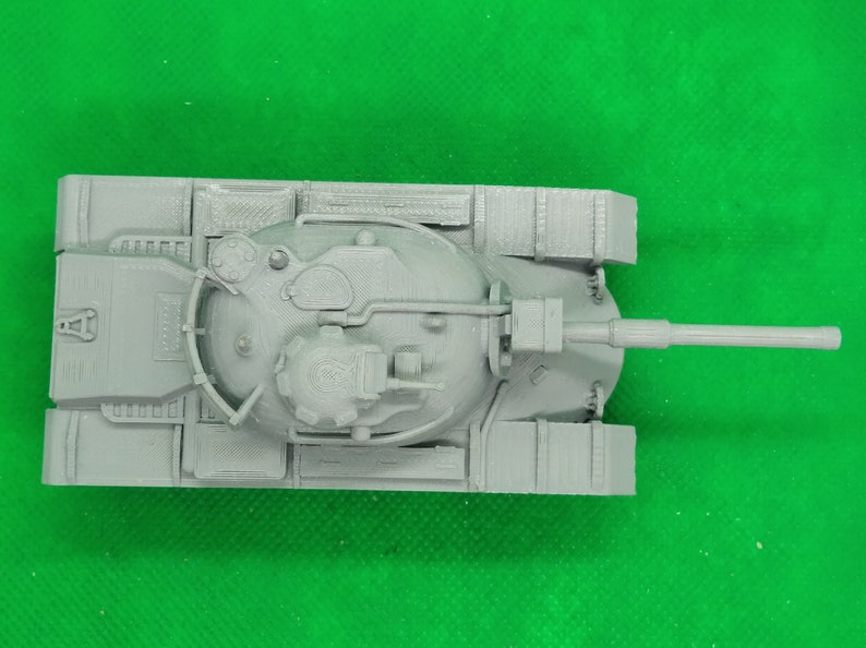 May include: A gray plastic model of a tank with a large turret and a long barrel. The tank has a detailed design with visible tracks and hatches.