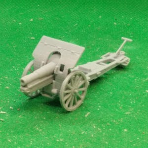 Può includere: Modello in miniatura grigio di un cannone di artiglieria con ruote a raggi, una canna lunga e uno scudo protettivo. Il modello è ambientato su uno sfondo verde, mostrando il suo design dettagliato e il tema storico.