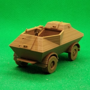 May include: A brown plastic model of a military armored car with a machine gun mounted on top. The car has four wheels and a rectangular body.