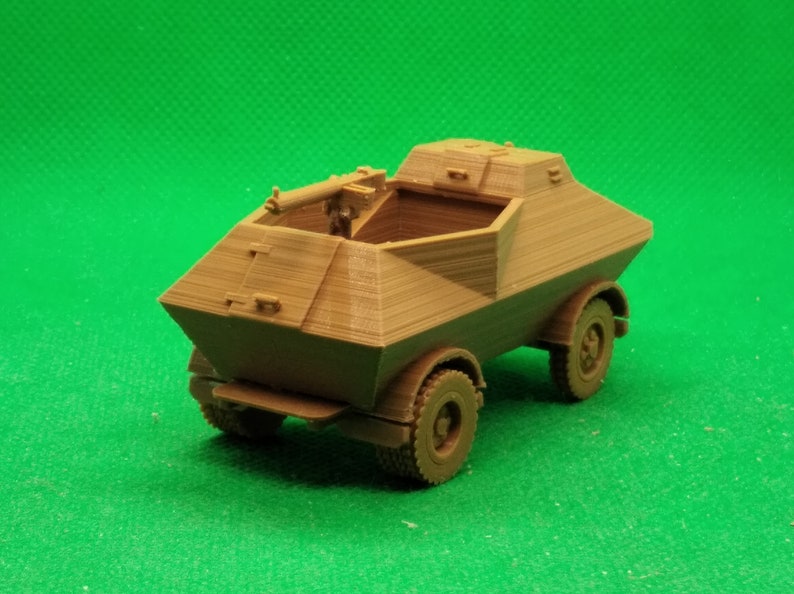 May include: A brown plastic model of a military armored car with a machine gun mounted on top. The car has four wheels and a rectangular body.