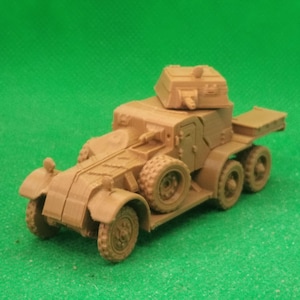 May include: A tan-colored model of an armored car, featuring six wheels and a turret. The vehicle has detailed features, including doors, fenders, and a rear storage area. The model is set against a green background.