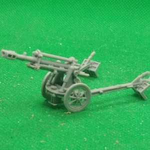 Puede incluir: Un modelo de plástico gris de un cañón antiaéreo de la Segunda Guerra Mundial. El cañón está sobre ruedas y tiene un cañón largo.