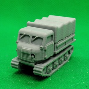Op de afbeelding: Een grijs, plastic model van een rupsvoertuig met een laadbak en een canvas afdekking. Het voertuig heeft een gedetailleerde cabine en een realistisch rupsbandensysteem.