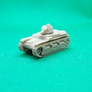 Op de afbeelding: Een klein, lichtbruin model van een tank met een gedetailleerd ontwerp. De miniatuurtank heeft een toren, rupsbanden en andere realistische componenten. Het model is waarschijnlijk gemaakt van plastic of een vergelijkbaar materiaal. De achtergrond is effen groen.