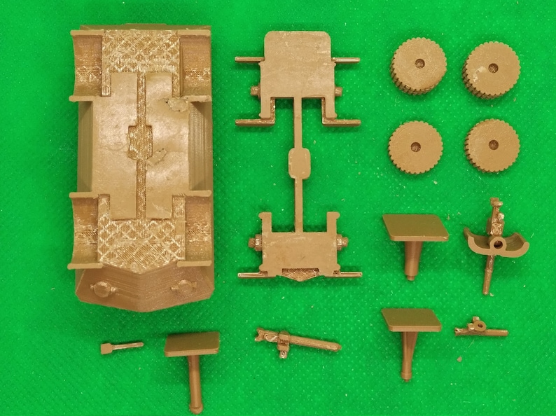 May include: A brown plastic model kit of a vehicle with multiple parts, including a chassis, wheels, and a gun turret. The kit is unassembled and ready to be built.
