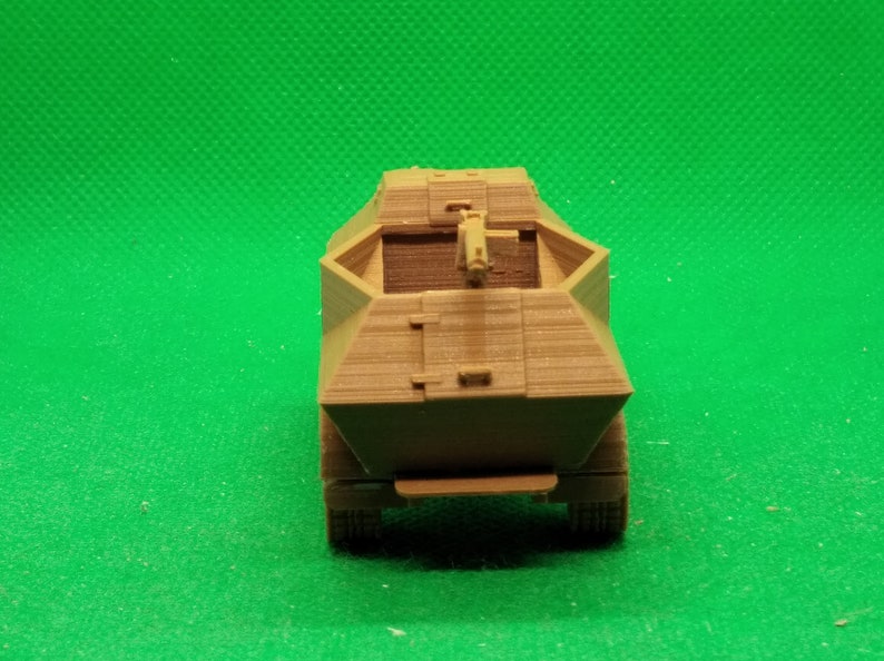 May include: A brown, plastic model of a military armored vehicle with a gun turret on top. The vehicle is on a green background.
