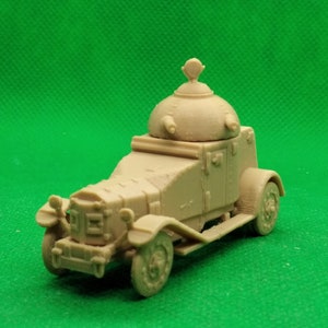 May include: A tan-colored model of an armored car with a rotating turret on top. The car has four wheels and a detailed exterior.