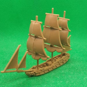 May include: A brown wooden model ship with three sails. The sails are raised and the ship is on a green surface.
