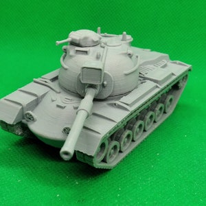 May include: A gray plastic model of a tank with a large turret and a long barrel. The tank has a detailed design with visible tracks and wheels.