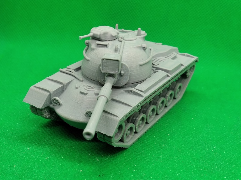 May include: A gray plastic model of a tank with a large turret and a long barrel. The tank has a detailed design with visible tracks and wheels.