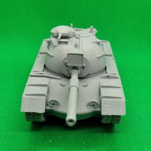 May include: A gray plastic model of a tank with a large cannon and a rounded turret. The tank has tracks and a detailed design.