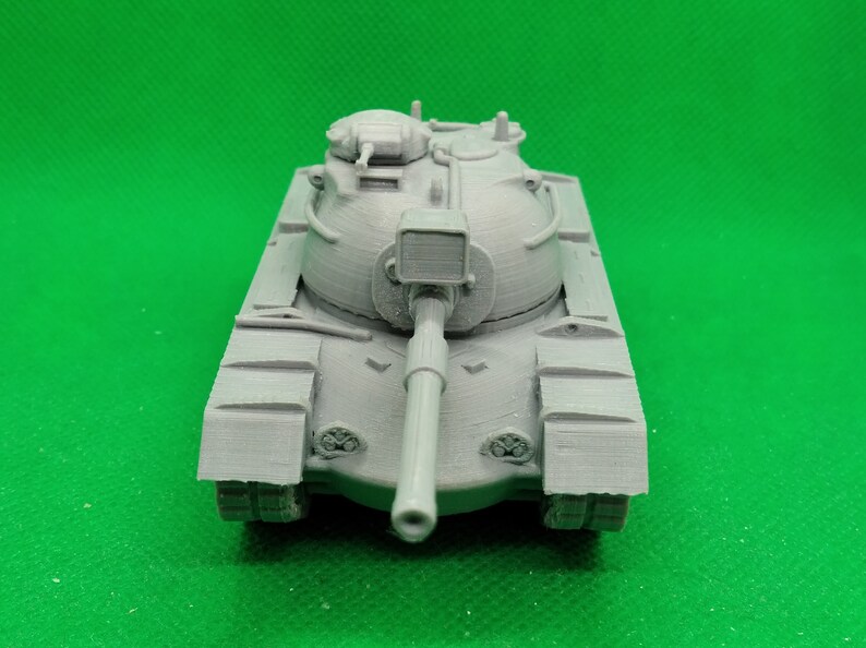 May include: A gray plastic model of a tank with a large cannon and a rounded turret. The tank has tracks and a detailed design.