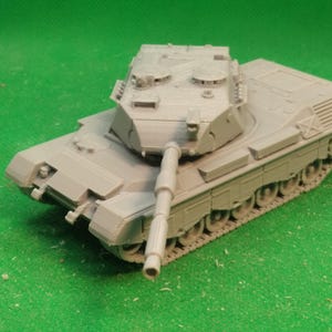 Puede incluir: Maqueta gris de un tanque con un cañón largo y orugas detalladas. El tanque tiene un cuerpo rectangular y una torreta con varias escotillas. El modelo está sobre un fondo verde.