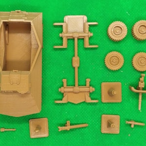 May include: A brown plastic model kit of a military vehicle. The kit includes the main body, chassis, wheels, and other small parts.