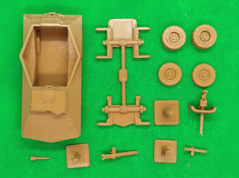May include: A brown plastic model kit of a military vehicle. The kit includes the main body, chassis, wheels, and other small parts.