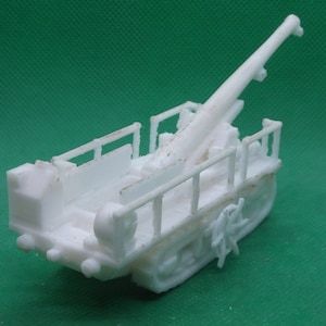Puede incluir: Modelo de plástico blanco de un cañón de artillería autopropulsado. El cañón está montado en un chasis de orugas y tiene un cañón largo.