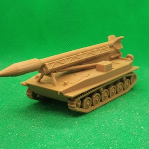 Puede incluir: Un modelo de plástico marrón de un vehículo militar de orugas con un lanzamisiles montado en la parte superior. El misil apunta hacia adelante y el vehículo tiene una serie de ruedas en las orugas.