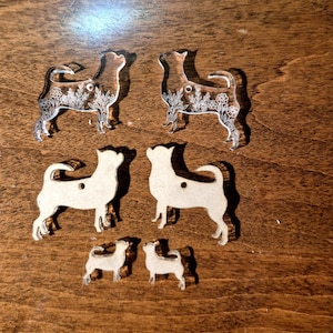 May include: Two clear acrylic dog-shaped charms featuring white floral line art, two opaque beige dog-shaped charms with a hole for hanging, and two smaller opaque beige dog-shaped charms, all arranged in a symmetrical pattern on a flat surface.