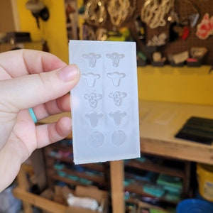 Peut inclure: Un moule en silicone transparent avec huit formes de t&ecirc;te de vache et deux formes rondes. Le moule est con&ccedil;u pour la fabrication d'objets en r&eacute;sine.