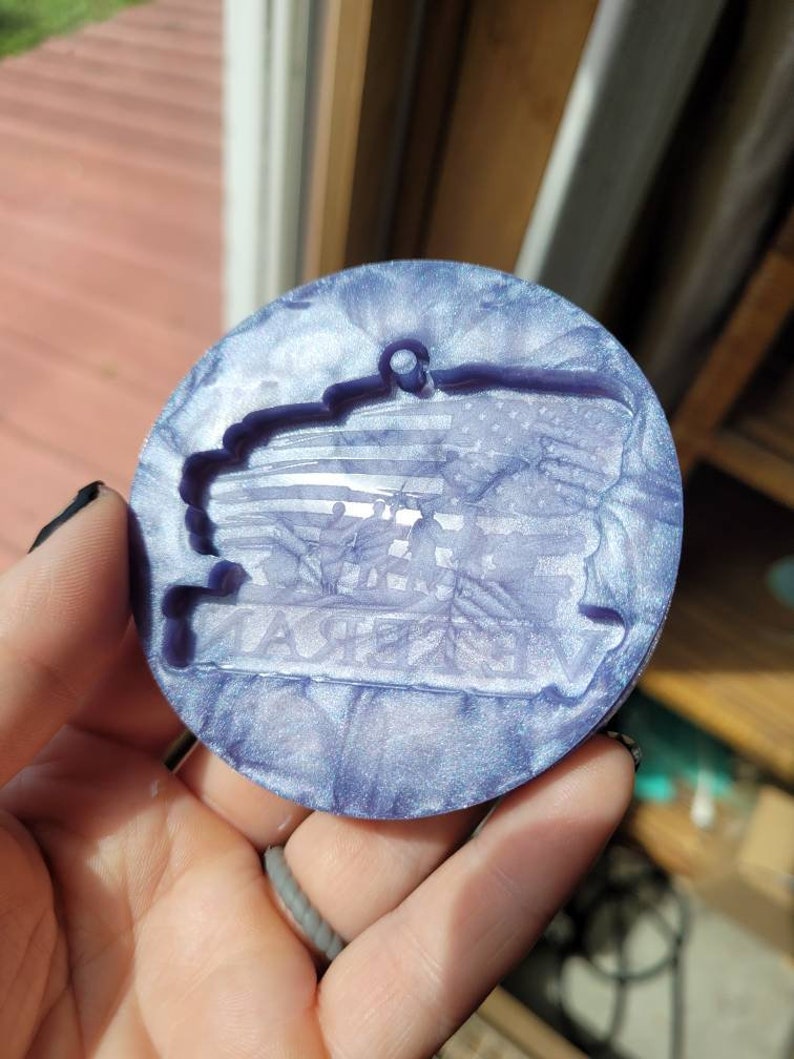 May include: A round, purple and white resin ornament with a raised design of an American flag and the words "Thank You" in a banner.