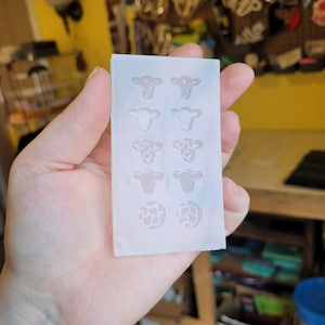 Peut inclure: Un moule en silicone blanc avec six cavit&eacute;s en forme de vache et deux cavit&eacute;s rondes avec un motif de vache. Le moule est con&ccedil;u pour la fabrication d'objets en r&eacute;sine.
