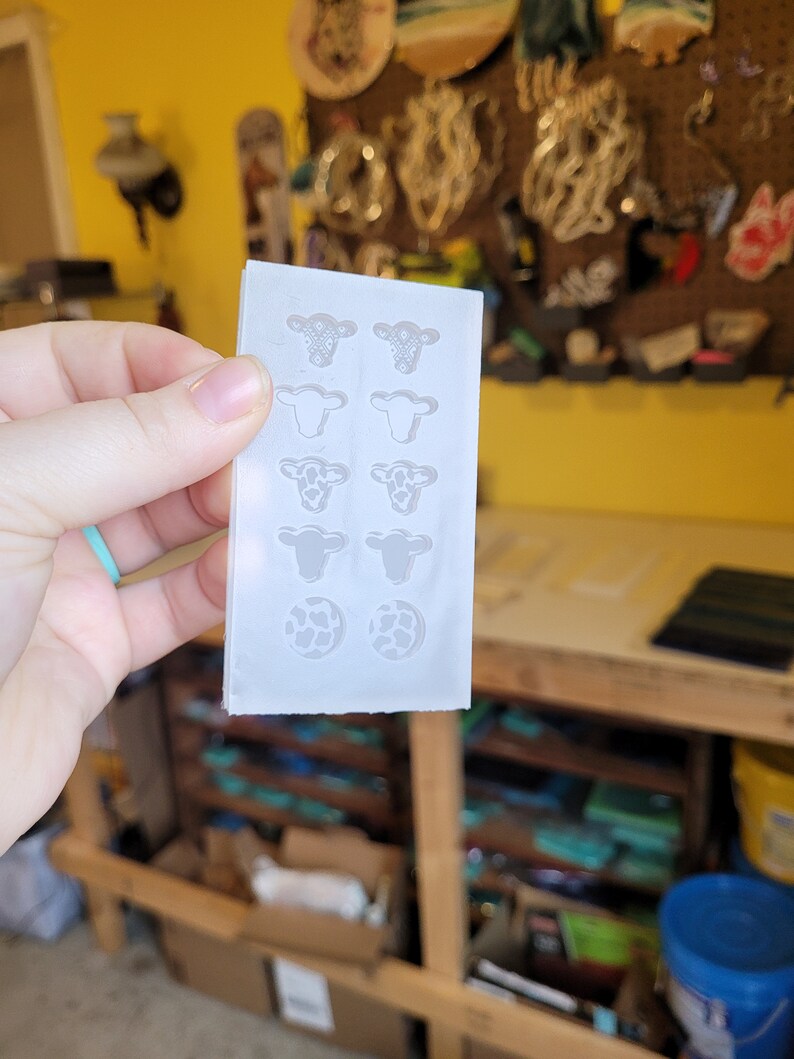 Peut inclure: Un moule en silicone transparent avec huit cavit&eacute;s en forme de vache et deux cavit&eacute;s rondes. Les cavit&eacute;s de vache ont des motifs diff&eacute;rents, notamment une vache avec un bandana, une vache avec des taches et une vache avec un c&oelig;ur. Les cavit&eacute;s rondes sont remplies d'un motif imprim&eacute; vache.