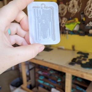 May include: A white silicone mould for making resin crafts. The mould is shaped like a tag and features a firefighter standing in front of an American flag.