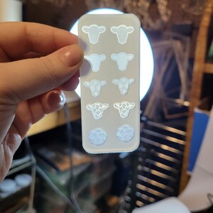 Peut inclure: Une feuille de plastique transparente blanche avec huit d&eacute;coupes en forme de vache. Les d&eacute;coupes sont de diff&eacute;rents motifs, dont une vache unie, une vache &agrave; motif floral et une vache &agrave; motif tachet&eacute;.