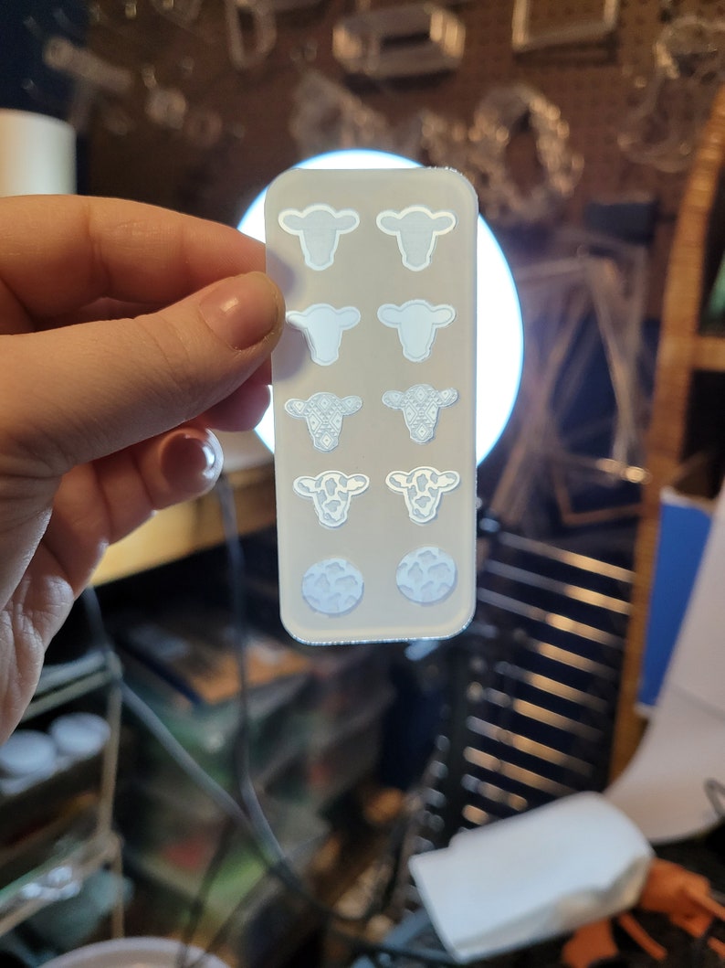 Peut inclure: Une feuille de plastique transparente blanche avec huit d&eacute;coupes en forme de vache. Les d&eacute;coupes sont de diff&eacute;rents motifs, dont une vache unie, une vache &agrave; motif floral et une vache &agrave; motif tachet&eacute;.