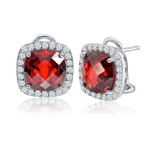 May include: A pair of silver earrings with a red gemstone surrounded by a halo of smaller white gemstones.