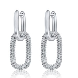 May include: Silver hoop earrings with a dangling oval-shaped link that is fully covered in small clear cubic zirconia stones.