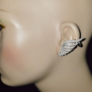 May include: A silver ear cuff with a wing design, encrusted with clear cubic zirconia stones.