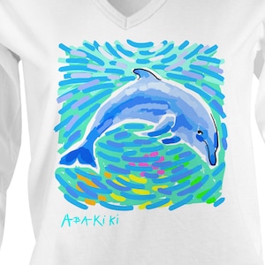 May include: White long-sleeve t-shirt with a colorful illustration of a dolphin jumping out of the water. The text "A*PA*KiKi" is printed on the shirt.