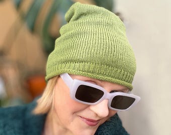 Puede incluir: Un gorro de punto color verde lima con un borde enrollado. El gorro presenta un patrón de punto jersey fino y uniforme en toda la corona y una textura acanalada a lo largo del borde inferior, ofreciendo un aspecto sencillo y limpio.