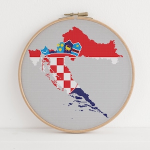 May include: A cross-stitch embroidery hoop depicting a map of Croatia with the Croatian flag colours. The map is outlined in white and the flag colours are red, white, and blue.