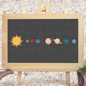 Puede incluir: Un patrón de punto de cruz del sistema solar sobre un fondo negro. El sol es amarillo, Mercurio es gris, Venus es naranja, la Tierra es azul y verde, Marte es rojo, Júpiter es naranja y blanco, Saturno es amarillo con anillos, Urano es azul y Neptuno es azul.